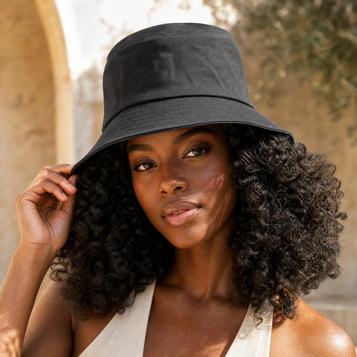 Woman with curly hair wearing the Damazo Sasha silk-lined bucket hat