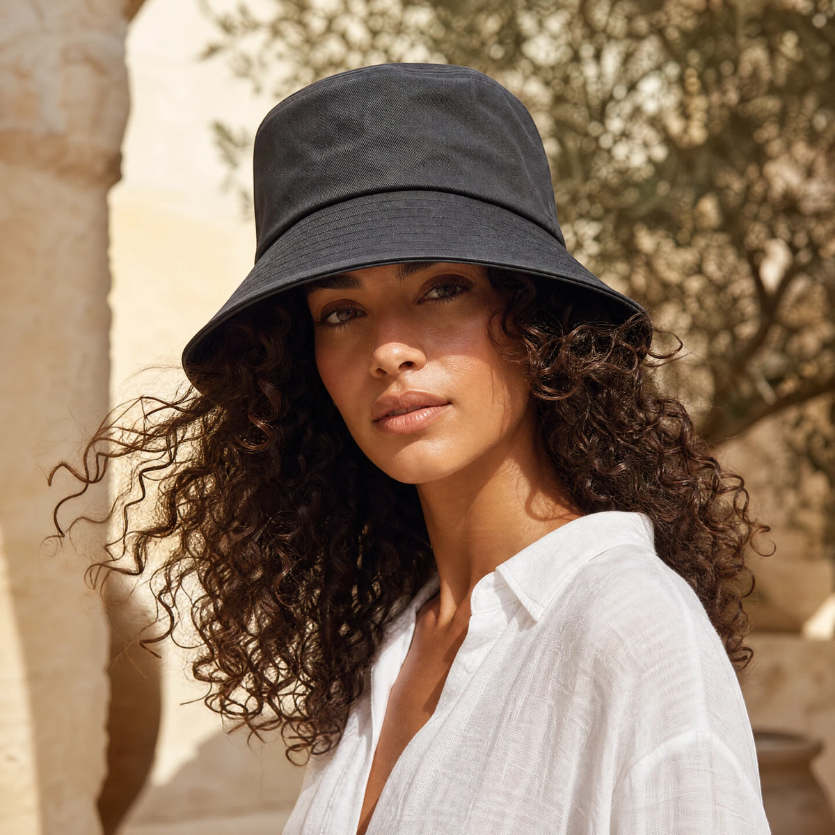 Woman with curly hair wearing the Damazo Sasha silk-lined bucket hat
